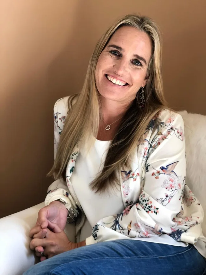 Renée Shearing smiling, seated, in a floral jacket