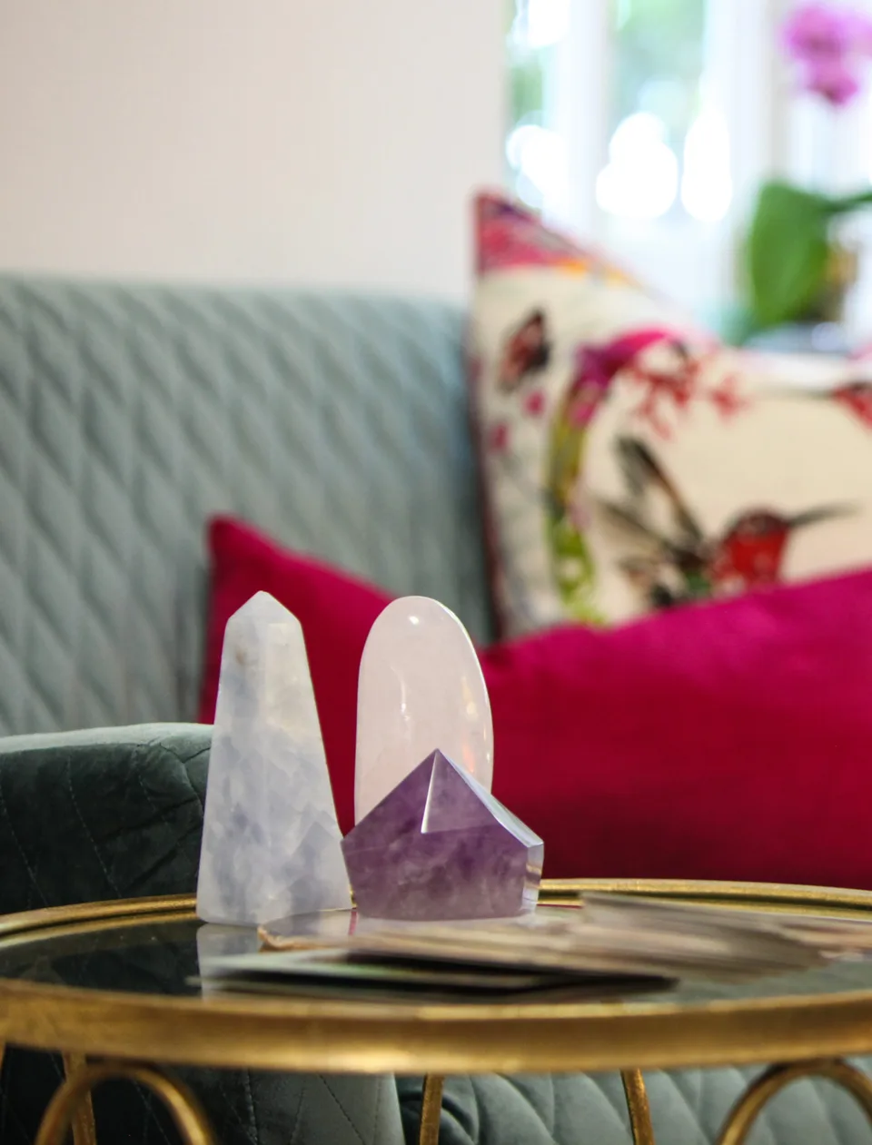Quartz and amethyst crystals on a gold-rimmed glass table in front of a grey sofa