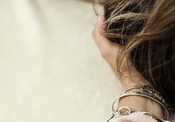 Close-up of a woman’s hand in her hair, silver bangles on her wrist