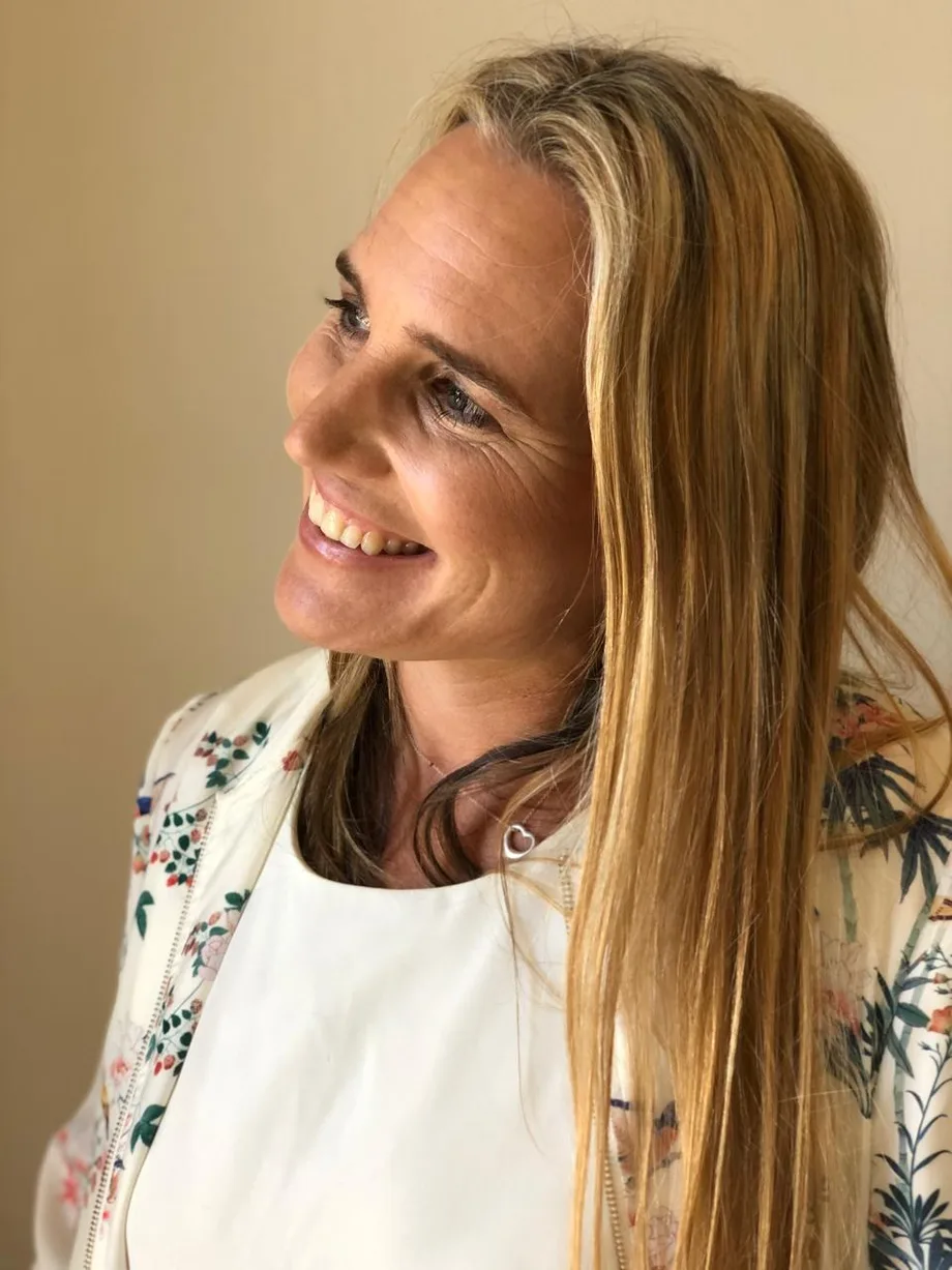 Renée Shearing smiling and looking to the side, in a floral jacket over a white top