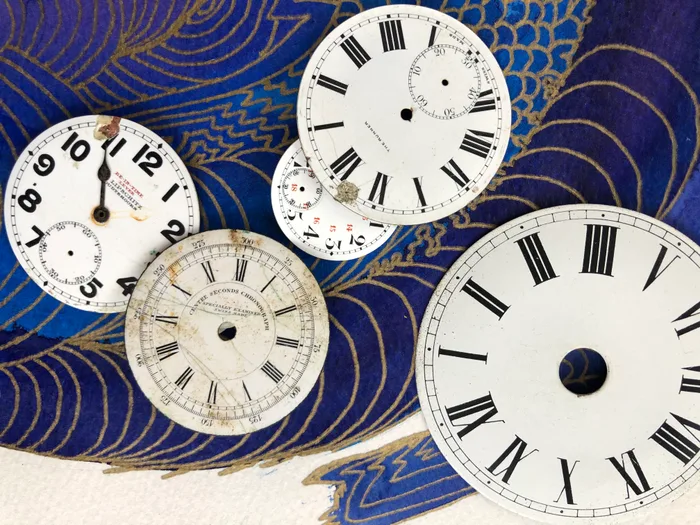 Collage of antique clock faces on deep blue with gold wave lines